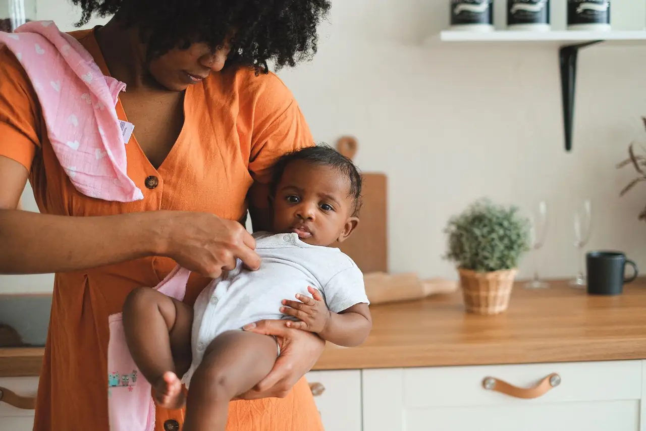 A loving mother holding her baby in a cozy kitchen, showcasing warmth and care.