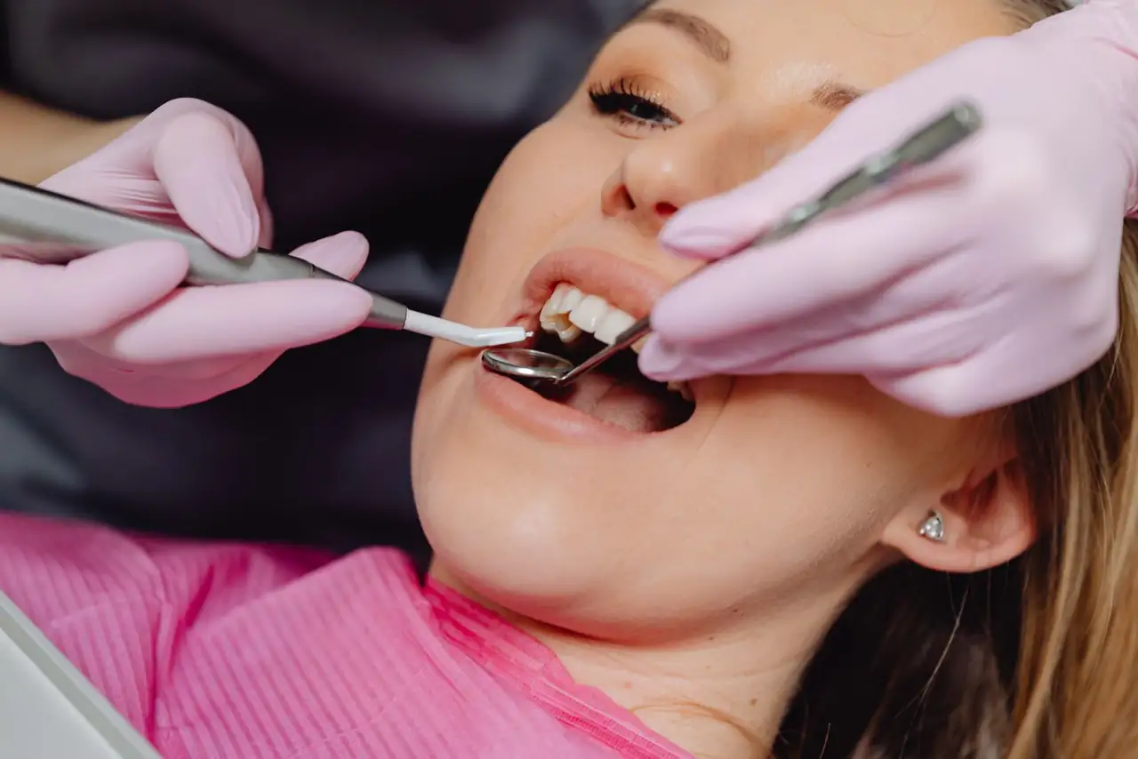 Close-up of a woman receiving dental care with a dentist using tools inside a clinic.